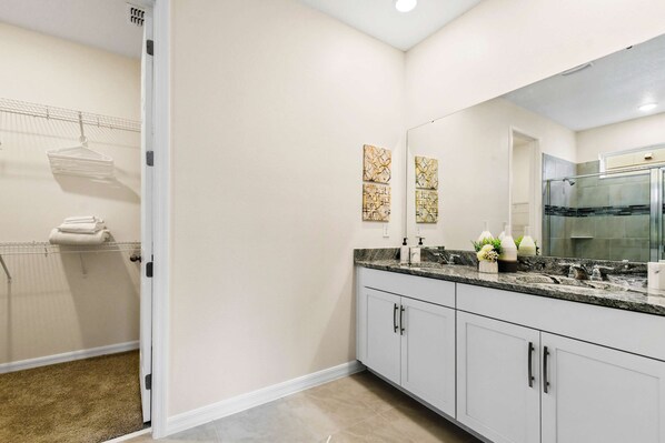 A modern bathroom with white cabinets, a granite countertop, and a large mirror.