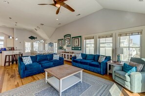 A spacious living room with two blue sofas, a wooden coffee table, and a patterned rug.
