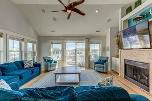 Amplia sala de estar con un conjunto de sofá azul, una mesa de centro y una chimenea.