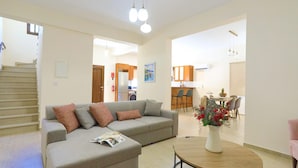 A modern living room with a sofa, a coffee table, and a dining area with chairs and a table. - Villa Lefkas in Malatya (Meladeia)