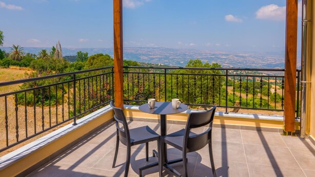 A balcony with a table and chairs, offering a view of a distant landscape. - Villa Lefkas in Malatya (Meladeia)