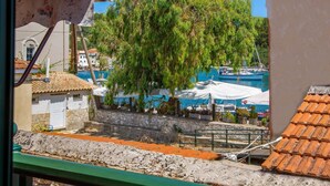 A coastal view with a tree, a boat, and a building with a tiled roof. - Doras House in Gaios (Paxos)