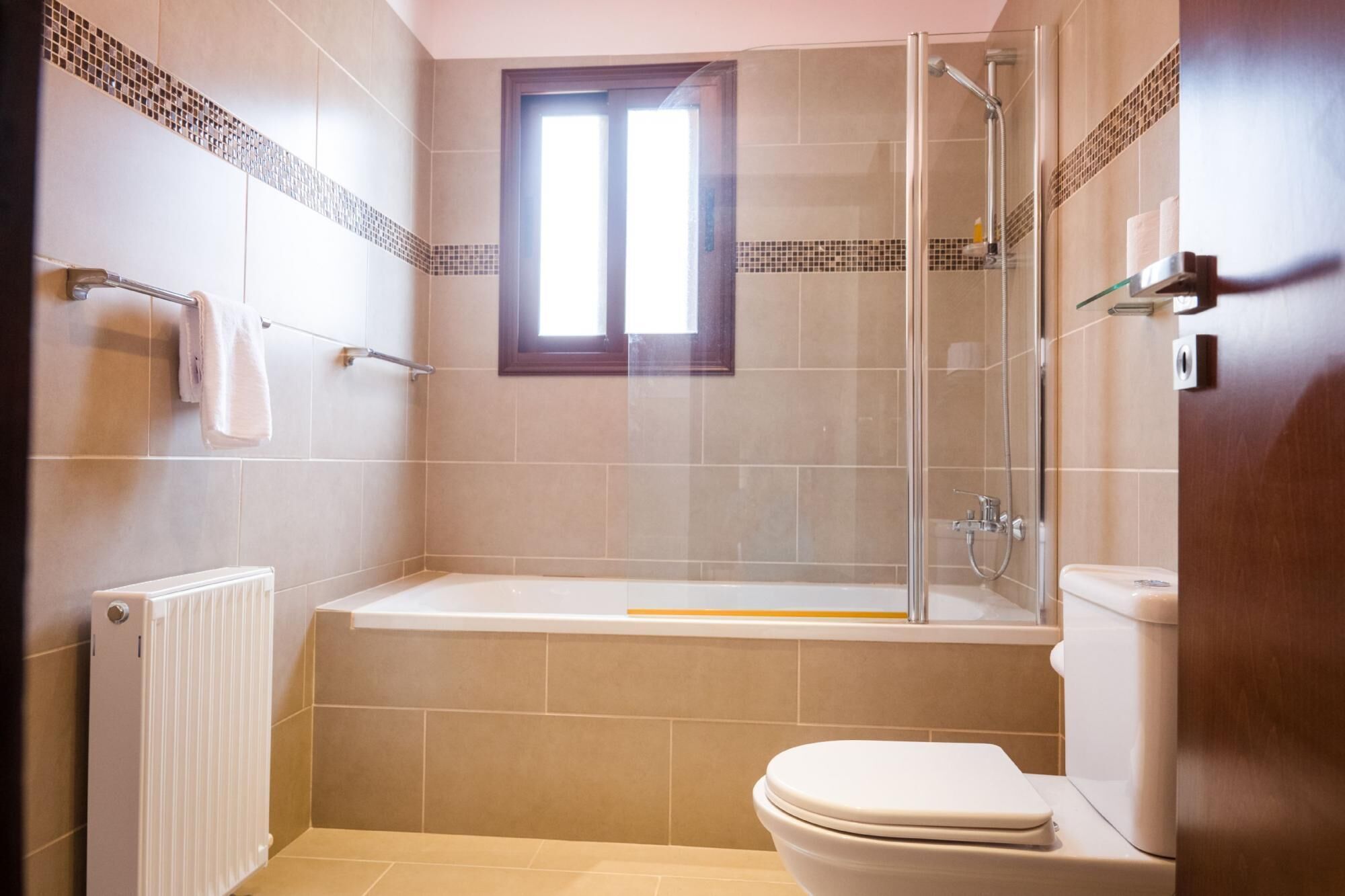 A bathroom with a glass-enclosed shower, a bathtub, and a toilet.