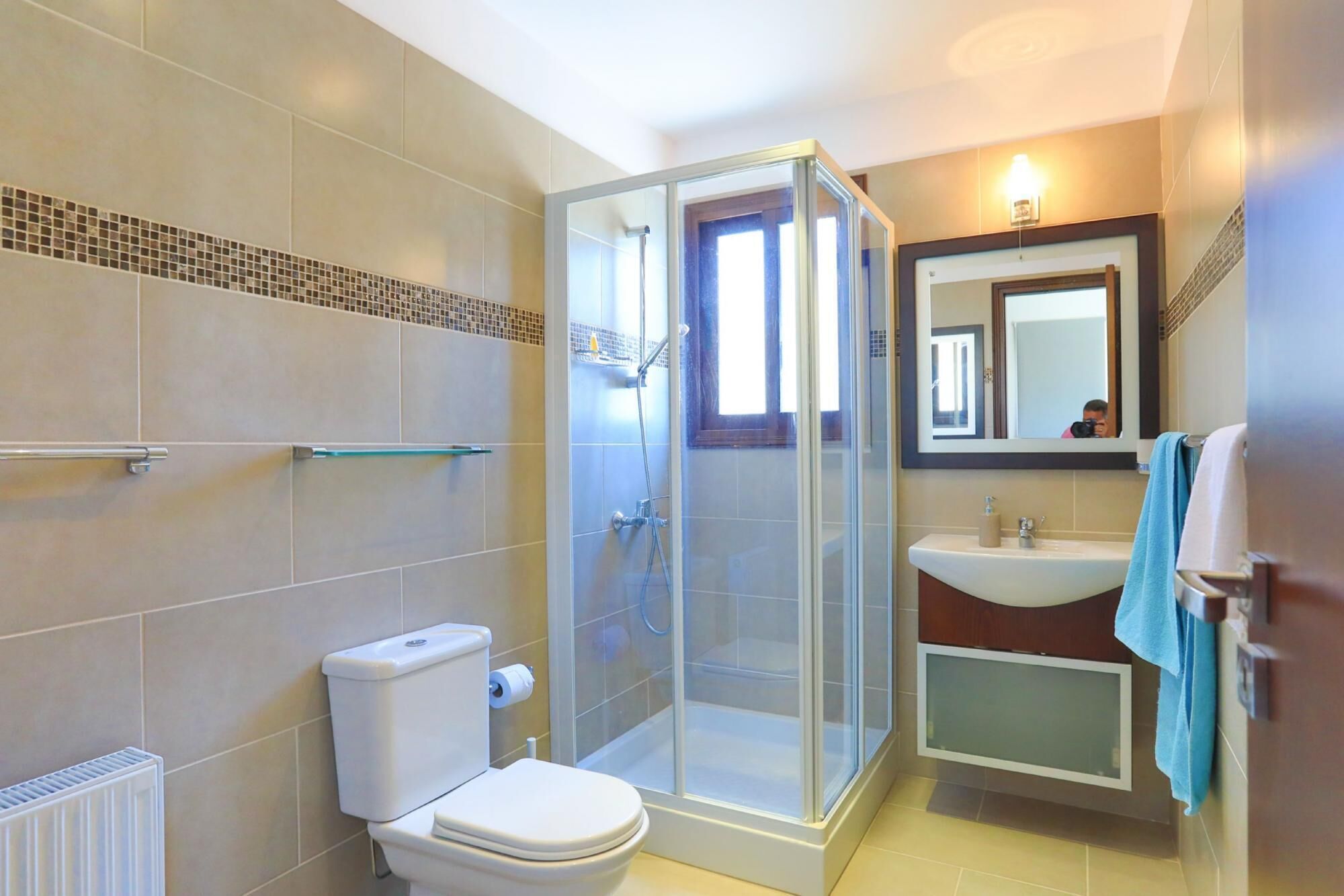 Un bagno con un water, una cabina doccia in vetro, un lavandino e uno specchio.
