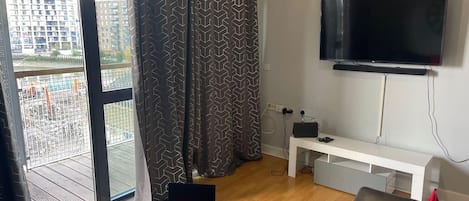 A modern living room with a large TV, a laptop, and a sofa.