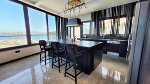 A modern kitchen with a large island, bar stools, and a view of the sea. - Çimentepe Residence Deluxe (Bodrum)