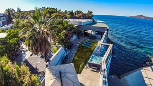 A coastal property with a pool, outdoor seating, and a view of the sea. - Çimentepe Residence Deluxe (Bodrum)
