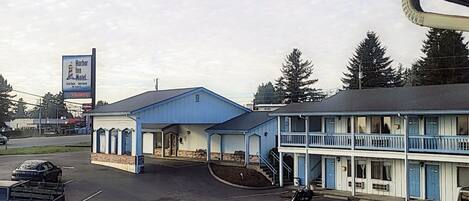 A motel with a blue exterior, a covered parking area, and a sign advertising the Harbor Inn Motel.