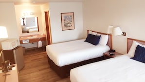 Ein Hotelzimmer mit zwei Betten, einem Badezimmer und einem Schreibtisch mit einer Mikrowelle.