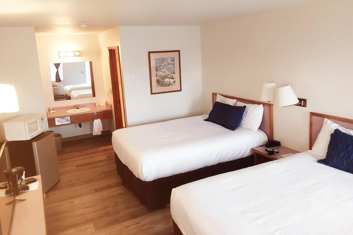Habitación de hotel con dos camas, baño y escritorio con microondas.