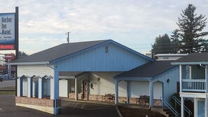 Ein Motel mit blauer Fassade, einer überdachten Veranda und einem Schild, das Zimmer frei weist.