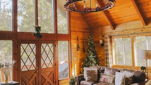 A cozy cabin interior with a leather sofa, a wooden ceiling, and a Christmas tree.