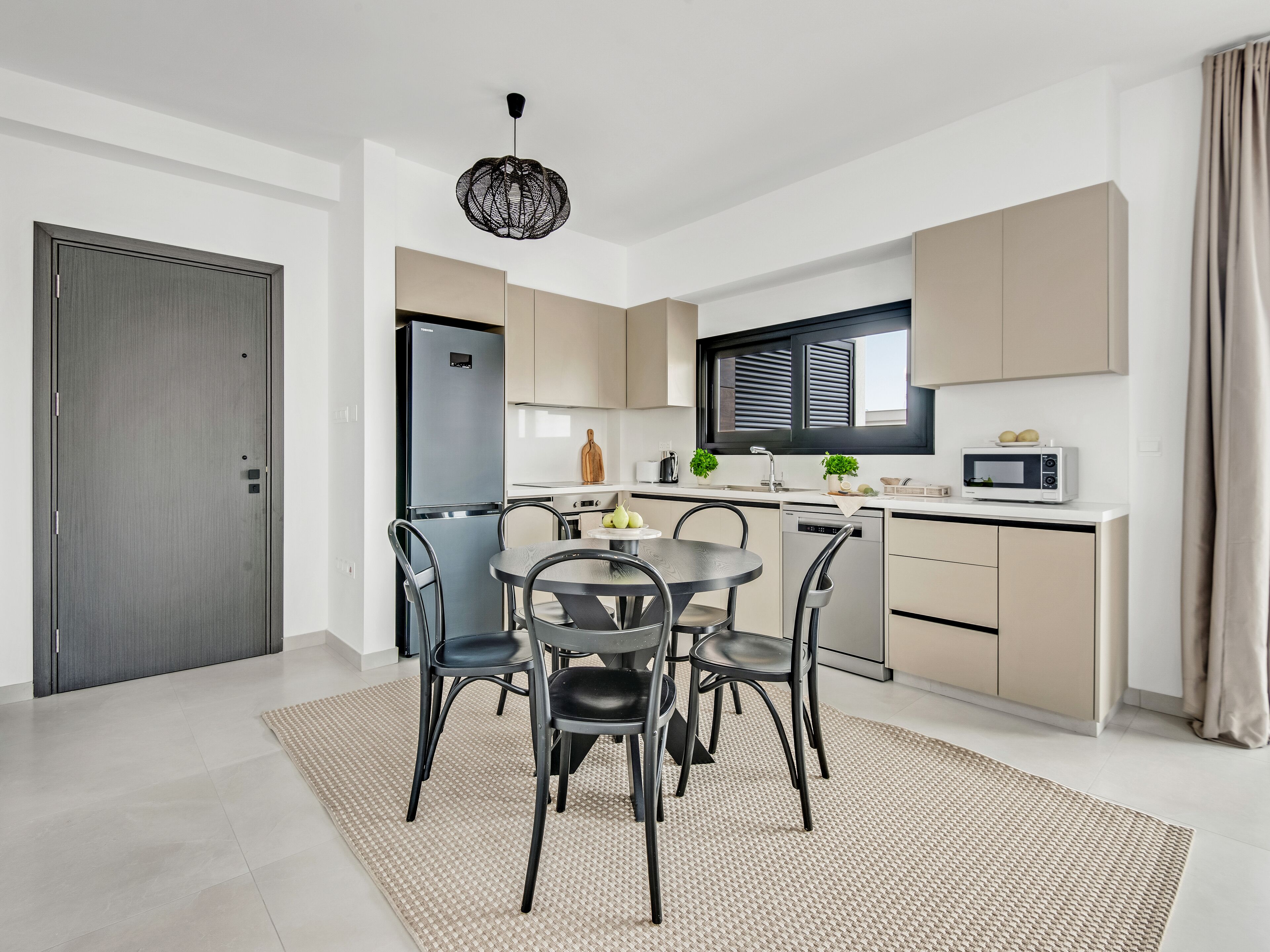 A modern kitchen with a dining area, featuring a built-in oven, microwave, and a dining table with chairs.