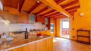 A kitchen with wooden beams, a granite countertop, and a view to the outside. - Viganello Panoramica (Lugano)