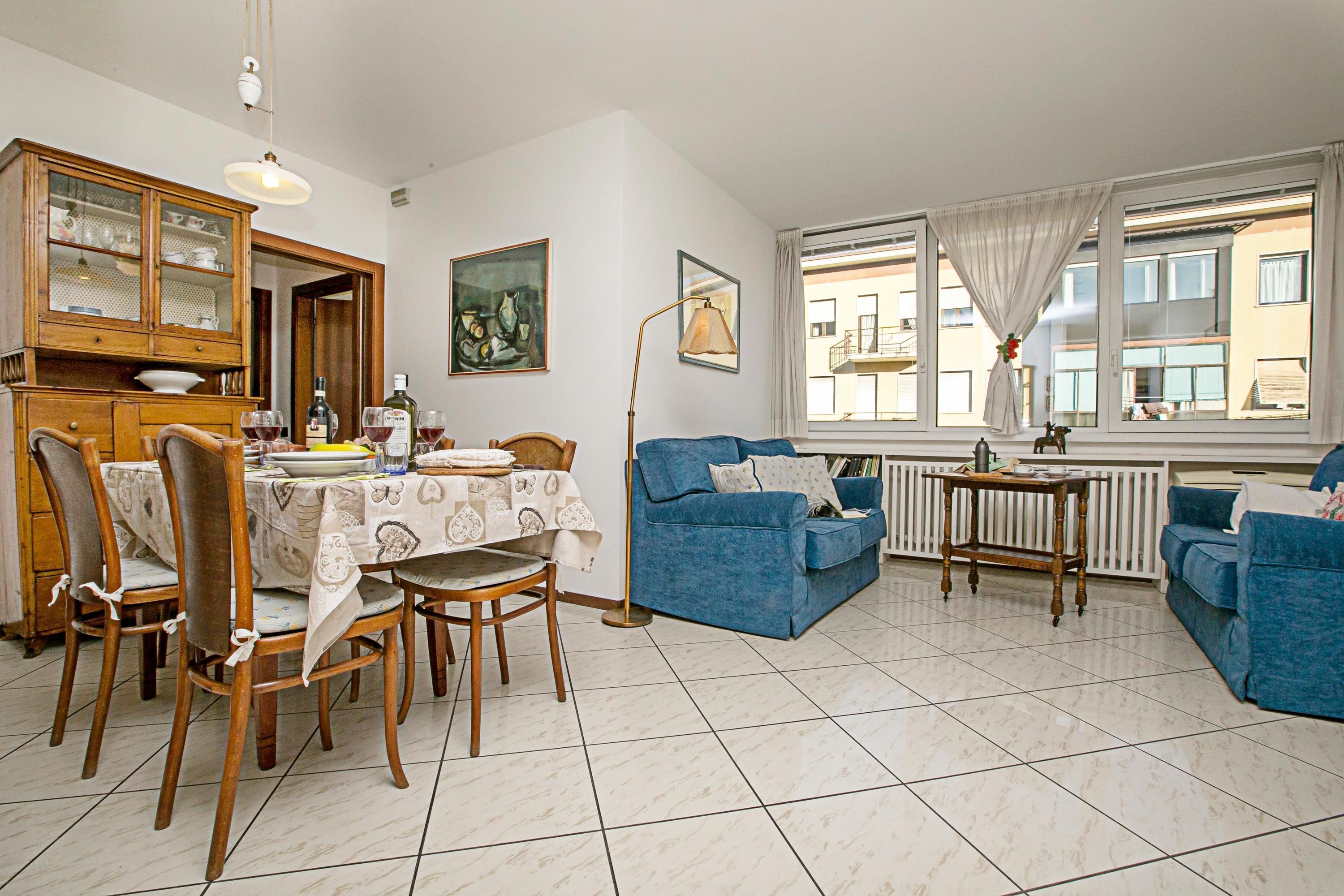 Un coin repas avec une table dressée pour quatre personnes, un canapé bleu et un meuble en bois.