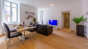 A modern living room with a dining area, a sofa, a TV, and a plant. - Heart of Lugano in Lugano (Lugano)