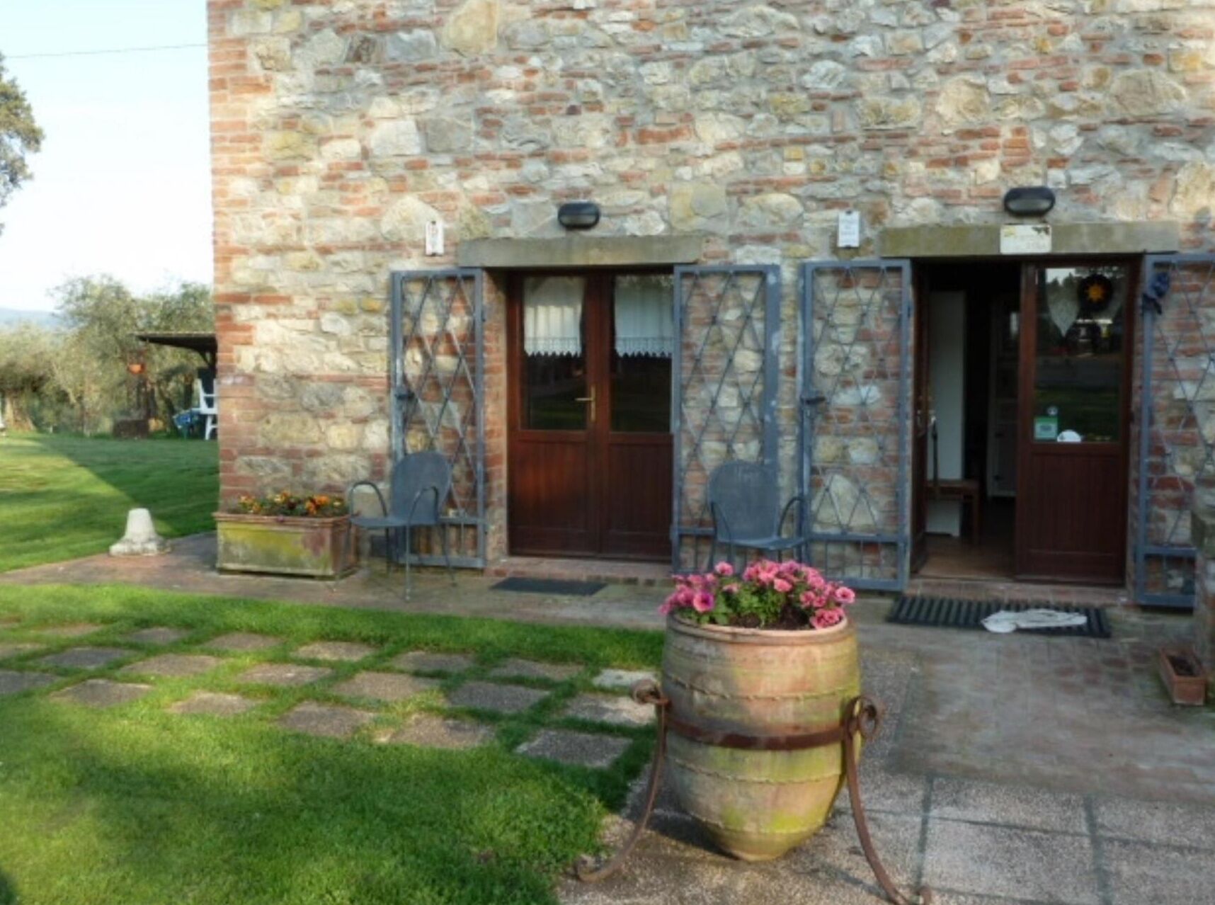 A stone building with a wooden door and a large potted plant in front.