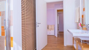 Een moderne badkamer met een houten vloer, een wit wastafelmeubel en een spiegel.