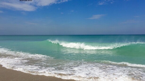 Uma praia com águas turquesa cristalinas e ondas suaves.
