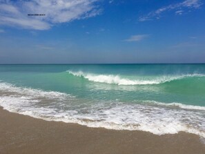 Een strand met helder turquoise water en rustige golven.