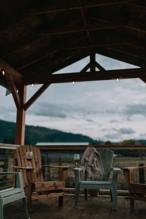 A covered outdoor seating area with wooden furniture and a view of the mountains. - Cozy Farmhouse in Mountains w/ hot tub & firepit (Rockport)