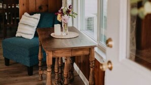 Una mesa de comedor de madera, un jarrón con flores, un sofá azul y una ventana con cortinas.