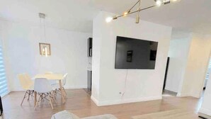 A modern living room with a large grey sofa, a wooden coffee table, and a dining area with a white table and chairs. - Stunning 3 bedroom single family home. (Windsor)