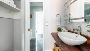 Une salle de bain moderne avec un lavabo blanc, un meuble-lavabo en bois et un miroir.