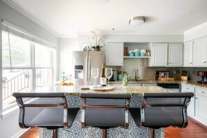 Uma cozinha moderna com uma ilha grande, banquetas e vista para o exterior.