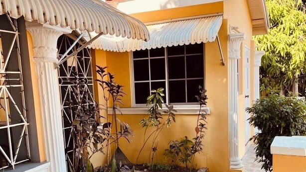 Una casa con patio de baldosas, una ventana y una planta al frente.
