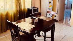 Comedor con mesa, sillas, ventilador de techo, televisor, microondas y refrigerador.