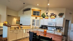 A spacious kitchen with white cabinets, a central island, and a hanging light fixture. - Remodeled with access to pools, pickleball, & golf in gated 55+ community! (Goodyear)