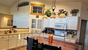 A spacious kitchen with a large island, white cabinetry, and a microwave. - Remodeled with access to pools, pickleball, & golf in gated 55+ community! (Goodyear)