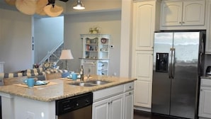 A kitchen with white cabinets, a stainless steel refrigerator, a granite countertop, and a built-in dishwasher.