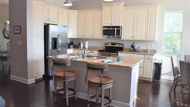 A modern kitchen with white cabinets, stainless steel appliances, and a central island with bar stools.