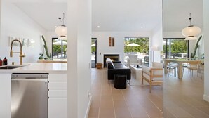 Eine moderne Küche mit Geschirrspüler, ein Essbereich mit Tisch und Stühlen sowie eine Lounge mit Feuerstelle.