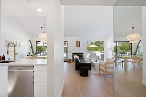 A modern kitchen with a dishwasher, a dining area with a table and chairs, and a seating area with a fire pit.