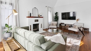 Un salon avec un canapé vert, une cheminée, un téléviseur et une table basse.