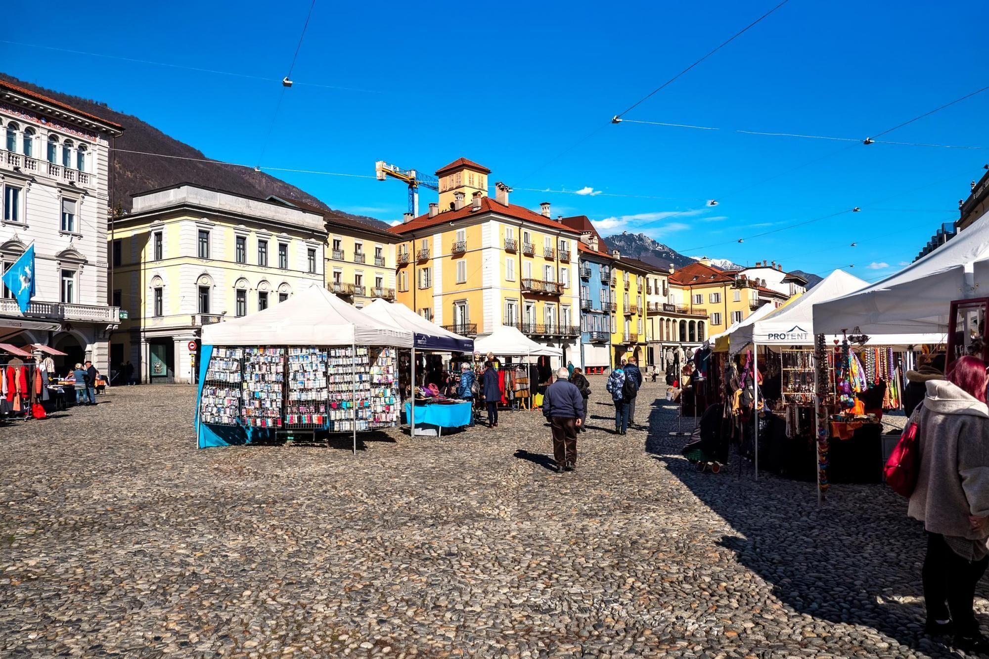Una piazza lastricata con bancarelle di mercato e edifici storici.
