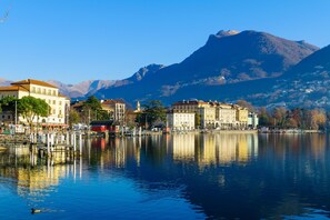 A waterfront view with buildings and mountains in the background. - Antico Municipio in Ponte Tresa (Tresa)