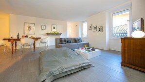 A modern living room with a sofa, coffee table, and a dining area with chairs and a table. - Antico Municipio in Ponte Tresa (Tresa)