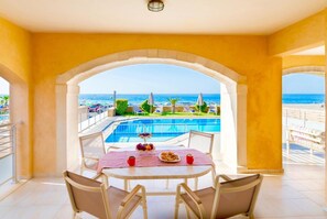 A dining area with a view of a pool and the sea.