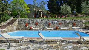 Una piscina con suelo de piedra y dos sillas reclinables.