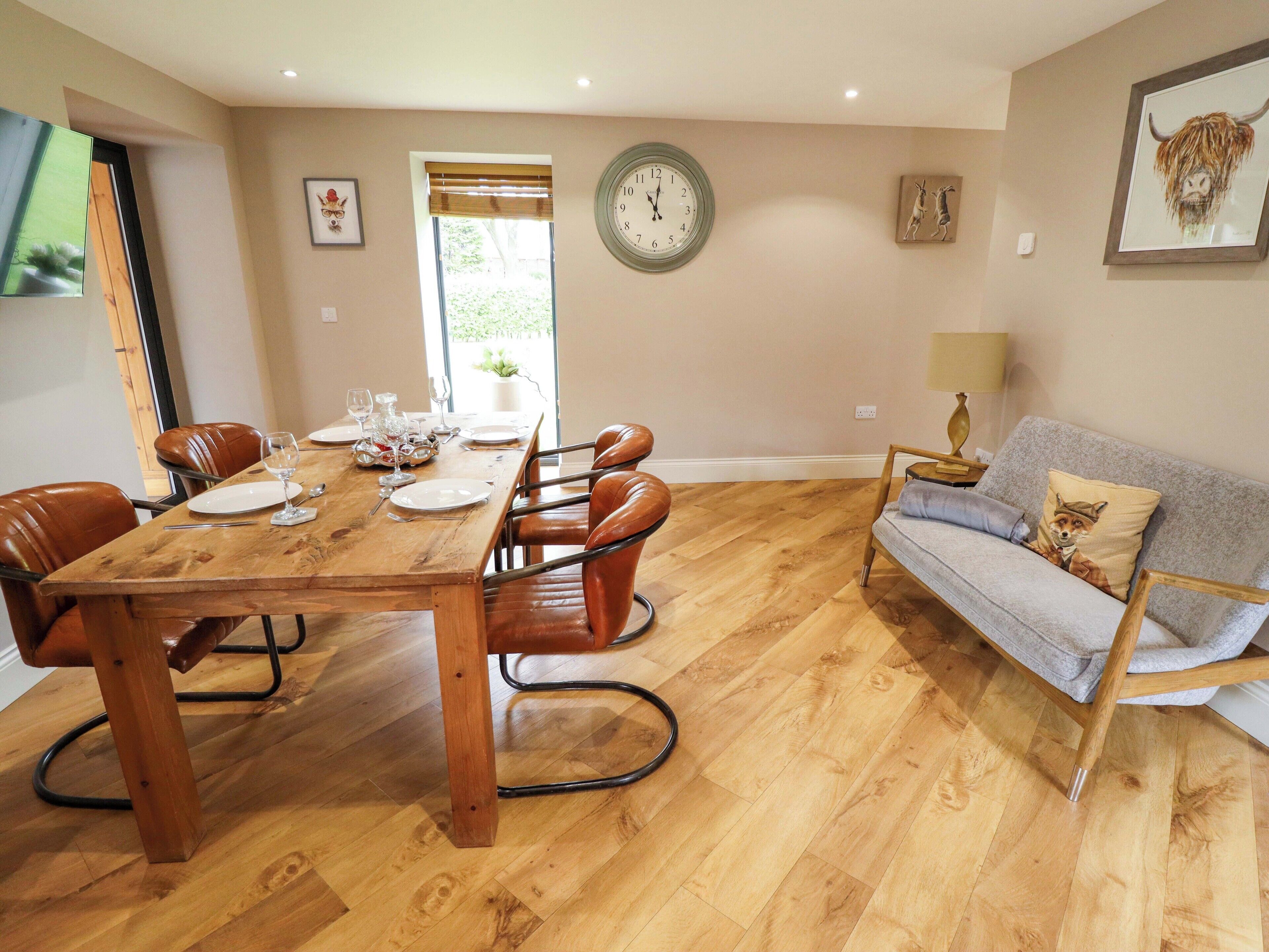 A dining area with a wooden table set for six, surrounded by leather chairs.