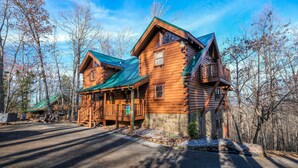 A log cabin with a green roof, a porch, and a stone foundation. - Smoky Treehouse Lodge #614 (Sevierville)