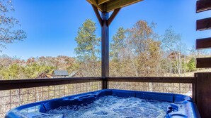 A hot tub on a balcony with a view of trees and a house in the background. - Sun Splash #342 (Sevierville)