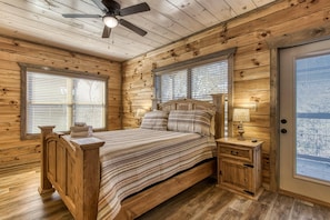 A wooden cabin bedroom with a bed, nightstands, and a ceiling fan. - Sun Splash #342 (Sevierville)
