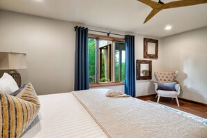 A bedroom with a large bed, a chair, a window with curtains, and a mirror on the wall. - Cosby Contemporary Cabin (Cosby)