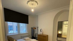 Ein Schlafzimmer mit Bett, Nachttischen, Heizkörper, Fenster und Spiegel.