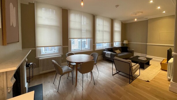 Ein modernes Wohnzimmer mit einem runden Esstisch, Sofas und einem Fernseher.